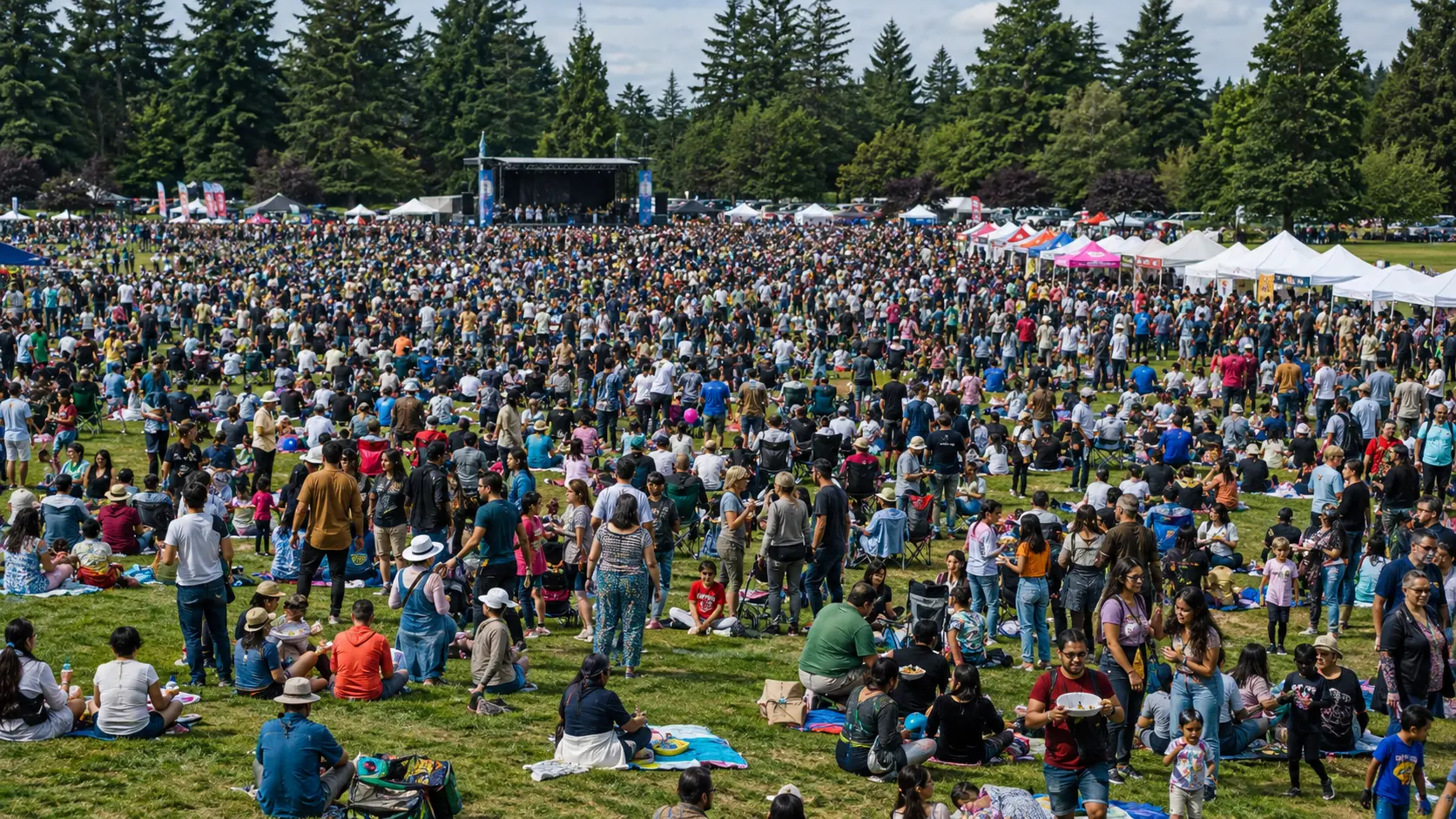 Thousands of festival-goers spread across a grassy field facing the main stage
